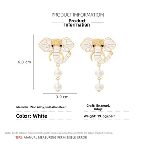 Macro shot of white enamel elephant earrings with faux pearls and size specs