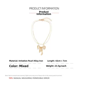 Detail of layered gold bow pendant and faux pearl necklace showing metal texture