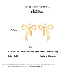 Detail of gold bow earrings with faux pearl center showing 4.7cm x 4cm size dimensions
