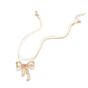 Detail view of double-layer necklace with pearl chain, gold snake chain and bow pendant