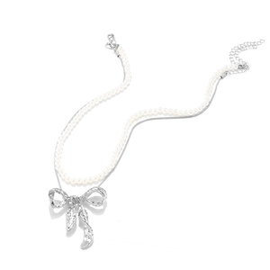Close-up of double-layer necklace with pearl chain, silver bow pendant and hammered texture