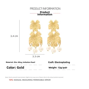 Detail view of gold alloy leaf earrings with triple pearls and 3.4x3.3cm size dimensions