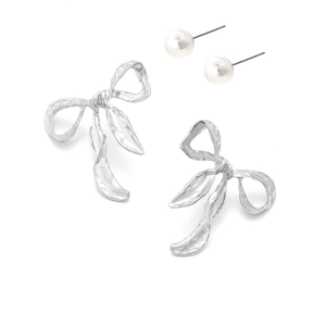 Detailed view of silver bow drop earrings with textured finish and white faux pearl studs