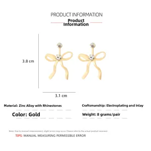 Macro detail of golden bow earrings with sparkling rhinestones and 3.8x3.1cm dimensions