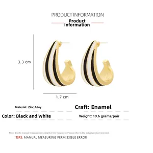Detail view of gold-tone C-shape earrings with black and white enamel, 3.3cm x 1.7cm size