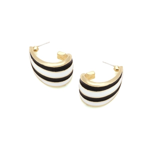 Detail of C-shaped gold hoop earrings with black and white enamel stripe patterns