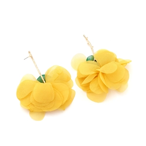 Detail of yellow chiffon flower earrings with golden branch-shaped studs on white background