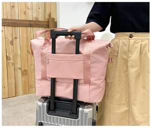 Detalle de bolsa de viaje rosa con banda para maleta y compartimento inferior separado