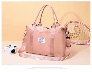 Detailed shot of pink nylon travel bag with adjustable strap and sturdy metal hooks