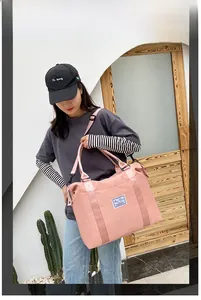 Pink nylon travel bag with adjustable strap shown in use by a model outdoors