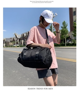 Outdoor street shot of a large black waterproof fitness travel bag with shoulder strap