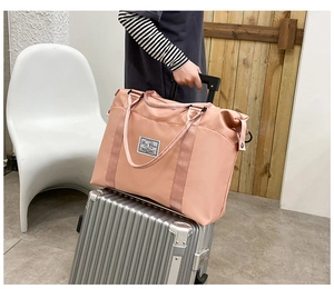 Pink nylon travel bag detail showing the luggage handle strap for easy carrying