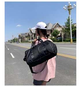 Large black nylon travel duffel bag for fitness with adjustable shoulder strap on model