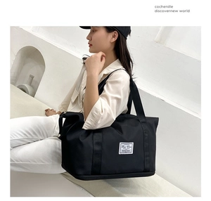 Close-up of black Oxford travel bag featuring wide straps and minimalist woven label