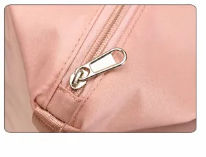 Detail of silver metal zipper puller on high-density pink nylon travel bag