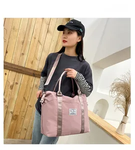 Pink nylon travel bag with wet-dry separation showing handle and adjustable strap detail