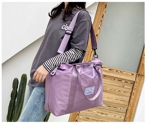 Purple nylon travel tote with waterproof fabric and adjustable shoulder strap shown on model