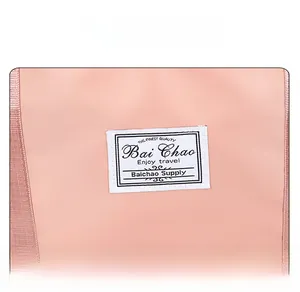 Detail of nylon travel bag showing a pink fabric texture and white logo label patch