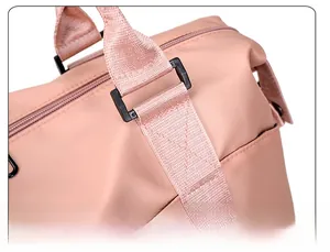 Detail of reinforced X-stitch and black buckles on pink nylon travel bag