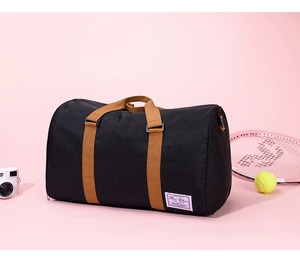 Detail of black canvas travel duffel bag with brown handles and tennis racket props