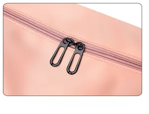 Close-up of pink nylon travel bag featuring durable dual black metal zippers and fabric texture