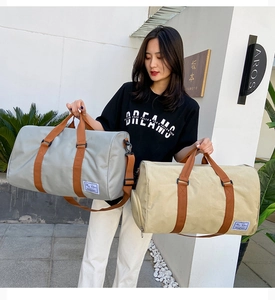 Outdoor shot of light grey and beige large canvas travel bags with brown strap handles