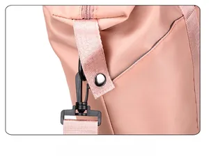 Close-up of pink nylon bag strap attachment with reinforced stitching and metal rivet