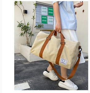 Detail of canvas travel bag featuring brown straps, side hardware and Bai Chao logo tag