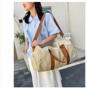 Close-up of a khaki canvas travel bag featuring a separate shoe compartment and shoulder strap