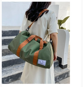 Outdoor shot of army green canvas travel bag featuring brown straps and branding label