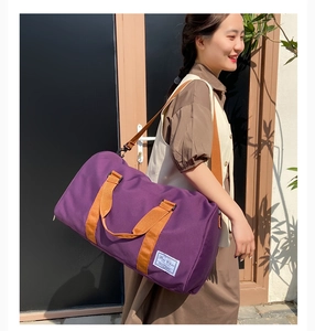 Purple canvas travel bag with brown straps shown on a model in an outdoor setting