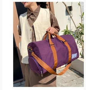 Detail of purple canvas travel duffel bag with brown nylon handles and adjustable strap