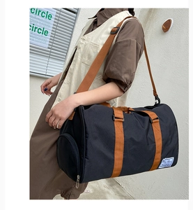 Detail of black canvas travel bag with brown straps and side zipper compartment