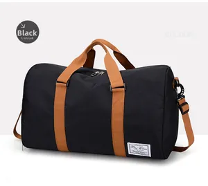 Detail view of black canvas duffel bag featuring brown handles and adjustable shoulder strap