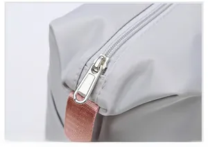 Detailed macro view of durable silver metal zipper and pink nylon handle on a travel bag