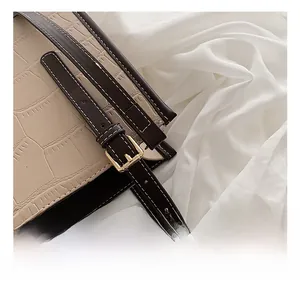 Detail of stone embossed tote bag showing golden buckle and white stitched leather strap