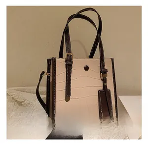 Detail showing the beige crocodile texture and brown contrast trim of the tote bag