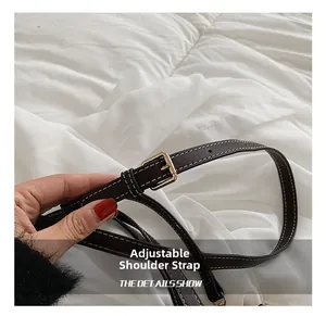 Detail of adjustable dark leather shoulder strap with white contrast stitching and gold buckle