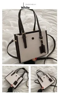 Detail of white crocodile pattern tote bag with brown trim and magnetic buckle closure