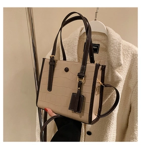 Detail of stone embossed pattern tote bag with brown contrast trim and metal buckle