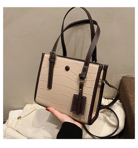 Close-up of crocodile embossed texture tote with vintage buckle and slim strap detail