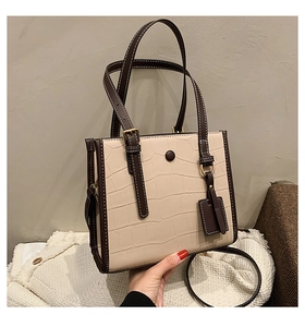 Detail of stone embossed pattern with contrast stitching on beige and brown tote bag