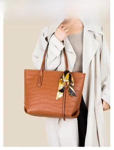 Brown crocodile embossed leather tote bag with printed silk scarf detail on a model