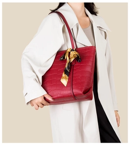 Detail of red croc-embossed tote bag with a decorative silk scarf on the handle