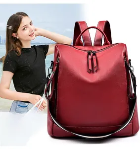 Dettaglio dello zaino in pelle rosso scuro con zip verticali e tracolla a righe