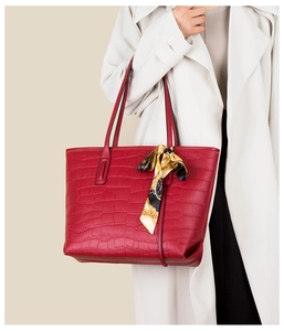 Macro view of red crocodile pattern tote bag featuring a decorative printed silk scarf
