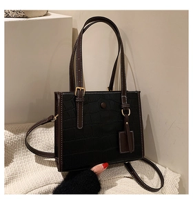Detail of black crocodile texture tote bag with brown straps and white contrast stitching