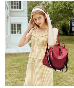 Dettaglio dello zaino in pelle PU bordeaux con tracolla intrecciata e tasca laterale