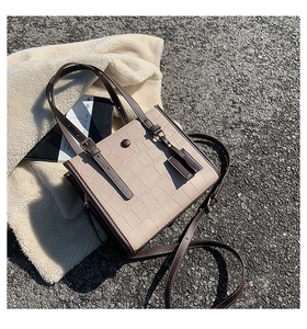 Detail of crocodile pattern faux leather tote bag with tassel and adjustable shoulder strap