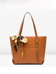 Detail of brown crocodile pattern tote bag with decorative printed silk scarf on handle